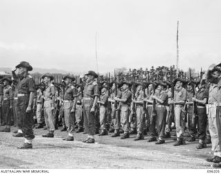 CAPE WOM, NEW GUINEA. 1945-09-13. TROOPS OF 6 DIVISION PRESENT ARMS FOR THE GENERAL SALUTE ON ARRIVAL OF MAJ-GEN H.C.H. ROBERTSON, GOC 6 DIVISION, AT CAPE WOM AIRSTRIP. LT-GEN H. ADACHI, COMD 18 ..