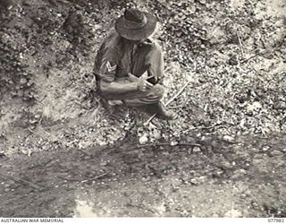 WUNUNG PLANTATION, NEW BRITAIN. 1944-12-30. QX39662 CORPORAL C. A. SMITH, 28TH MALARIA CONTROL UNIT ATTACHED TO HEADQUARTERS, 5TH DIVISION, TREATING A SMALL JUNGLE STREAM WITH DDT OIL