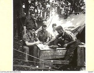 FINSCHHAFEN AREA, NEW GUINEA. 1943-11-13. CONDUCTING A SWEEP ON THE MELBOURNE CUP AT HEADQUARTERS, 9TH AUSTRALIAN DIVISION. SHOWN ARE: CAPTAIN L. T. ALLEN (1); SX3739 PRIVATE B. K. ASHTON (2); ..