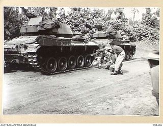 TOROKINA AREA, BOUGAINVILLE. 1945-07-28. CAPTAIN ROWLEY EXAMINING THE TRACKS OF AN M24 GENERAL CHAFFEE LIGHT TANK WHICH WERE CLEANED BEFORE THE TRIALS FOR TESTS TO BE CONDUCTED FOR THE WAR OFFICE