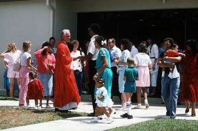 A priest greets parishioners, including airmen, after mass