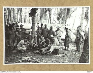 SIALUM BEACH, NEW GUINEA. 1944-01-08. A UNITED STATES INTERPRETOR, ATTACHED TO THE 9TH AUSTRALIAN DIVISION QUESTIONING A WOUNDED JAPANESE SOLDIER BEFORE AN AUDIENCE OF INTERESTED SPECTATORS