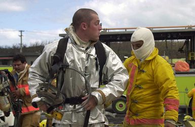 US Air Force (USAF) AIRMAN First Class (A1C) Billy Weinstein from the 36th Civil Engineer Squadron (CES), Fire Protection Flight stationed at Andersen Air Force Base (AFB), Guam, gets help putting on his Self Contained Breathing Apparatus (SCBA) from another firefighter during a fuel tank fire at the Cabras Island tank farm