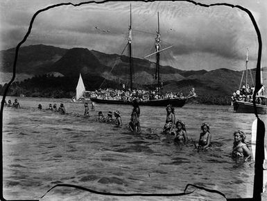 [Group of Pacific Island people in water with ships in background]