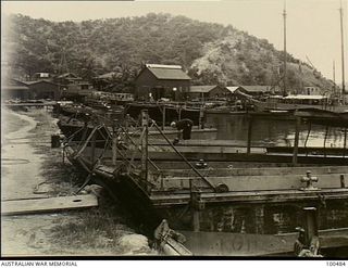 Port Moresby, New Guinea. 1944-05-30. A general view of 1 Watercraft Workshop, Australian Electrical and Mechanical Engineers (AEME), showing a lugger moored at the wharf and small craft tied up on ..