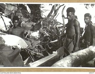 ULUGUDU, NEW GUINEA, 1943-10-25. NATIVE BOYS EMPLOYED BY THE AUSTRALIAN AND NEW GUINEA ADMINISTRATIVE UNIT (ANGAU), CHECKING THE WRECKAGE OF A MITCHELL BOMBER AIRCRAFT IN THE JUNGLE