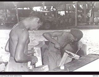 TOROKINA, BOUGAINVILLE, 1945-12-04. PRIVATE C. BENJAMIN (1) AND SAPPER R. C. KELLY (2) WORKING IN THE TINSMITHING AND PLUMBING SECTION OF THE TOROKINA REHABILITATION TRAINING CENTRE