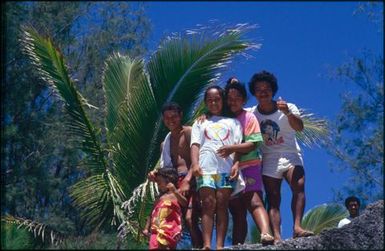 Group of children looking down at the camera from a rocky ridge