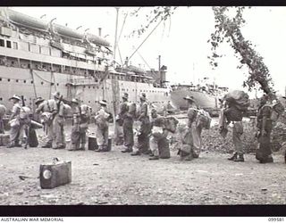 LAE, NEW GUINEA, 1945-11-20. TROOPS OF LAE BASE SUB AREA SLOWLY MAKE THEIR WAY ABOARD THE TROOPSHIP MV DUNTROON FOR RETURN TO AUSTRALIA. IN THE BACKGROUND CAN BE SEEN THE UNITED STATES TROOPSHIP SS ..