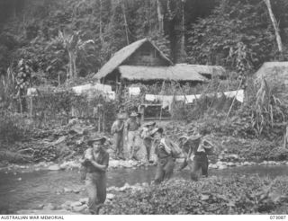 BASU RIVER VALLEY, NEW GUINEA. 1944-05-14. MEMBERS FROM THE NEARBY 15TH INFANTRY BATTALION CROSSING A CREEK WHICH FLOWS THROUGH A CHINESE FARMING VILLAGE APPROXIMATELY 7 MILES FROM LAE. THEY CARRY ..