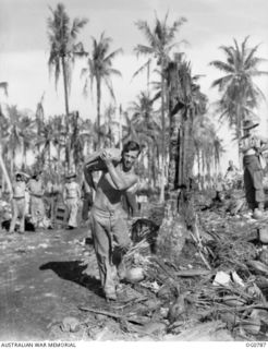 LOS NEGROS ISLAND, ADMIRALTY ISLANDS. 1944-03-18. LEADING AIRCRAFTMAN J. G. KENNAR RAAF, COONABARABRAN, NSW, WELTERWEIGHT WRESTLING CHAMPION OF NEW GUINEA, MAKES LIGHT OF CARRYING A BAG OF SUGAR ..
