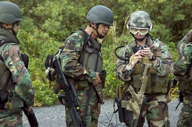 US Navy (USN) Operation SPECIALIST 2nd Class (OS2) Jody Heflin, Detachment 53 (Det.53), Explosive Ordnance Disposal Mobile Unit 5 (EODMU-5), instructs Republic of Singapore Navy (RSN) Sailors in the proper use of a global positioning unit during Exercise TRI-CRAB 2006, onboard USN Santa Rita Naval Base (NB), Guam (GUM). TRI-CRAB 2006 is an annual multi-national explosive exercise designed to increase the interoperability skills of USN, RSN, and Royal Australian Navy (RAN) EOD technicians in a friendly, forward-deployed environment