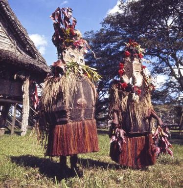 Dancers in elaborate costumes dance outside Angoram Haus Tambaran, East Sepik District, Papua New Guinea, approximately 1968 / Robin Smith