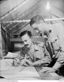 AITAPE, NORTH EAST NEW GUINEA. C. 1944-06. FLYING OFFICER M. E. COLLARD, BRIGHTON, VIC (LEFT), AND LEADING AIRCRAFTMAN D. W. SINCLAIR, WEST END, QLD, IN THE DRAWING OFFICE OF NO. 13 SURVEY AND ..