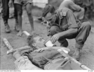 YAULA, NEW GUINEA. 1944-04-10. VX108664 CORPORAL E. ANTHERSON, 57/60TH INFANTRY BATTALION (1), WOUNDED IN ACTION, RECEIVES A DRINK OF COFFEE FROM MR. W.A. ALVEN. (2), THE SALVATION ARMY RED SHIELD ..