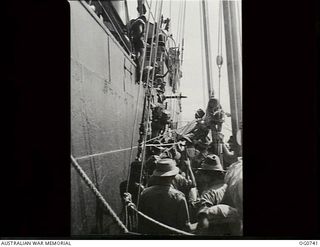 MILNE BAY, PAPUA. C.1944-02. AIRMEN OF NO. 75 SQUADRON RAAF CLIMBING FROM A RAAF LUGGER UP THE SHIP'S SIDE EN ROUTE FROM MILNE BAY TO LAE