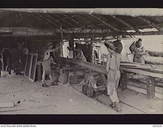 SOGERI VALLEY, NEW GUINEA, 1943-06-26. NEW GUINEA FORCE SCHOOL OF SIGNALS SAW BENCH, EQUIPPED WITH A 24" CIRCULAR SAW, DRIVEN BY A FORD V8 ENGINE. ALL THE TIMBER FOR THE CAMP CONSTRUCTION IS CUT ..