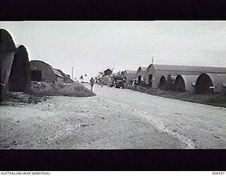 LOMBRUN POINT. ADMIRALTY ISLANDS. 1947-07. QUONSET HUTS FLANK A ROAD AT THE SHIP REPAIR BASE. COMMANDER WRIGHT IS IN THE FOREGROUND. (NAVAL HISTORICAL COLLECTION)