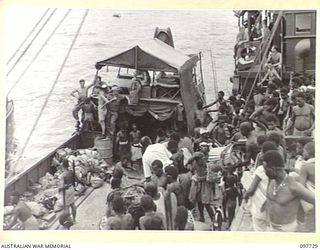 KAHILI, BOUGAINVILLE. 1945-10-02. 350 NATIVES WHO WERE EVACUATED FROM THE BUIN AREA TO FAURO ISLAND BY THE JAPANESE RETURNED TODAY ON THE 300-TON VESSEL NEENA. THEY ARE SHOWN GOING OVER THE SIDE OF ..