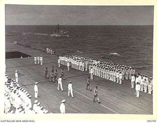 AT SEA OFF RABAUL, NEW BRITAIN. 1945-09-06. LIEUTENANT GENERAL V.A.H. STURDEE, GENERAL OFFICER COMMANDING FIRST ARMY, AND PARTY, WALKING BETWEEN THE LINES OF SAILORS ON THE FLIGHT DECK OF THE ..