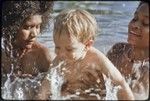 Young women taking care of an Australian child named Butch Holland, play in water