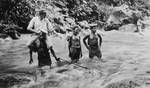 Native constables and patrol officer? crossing river, New Guinea, c1924 to ?