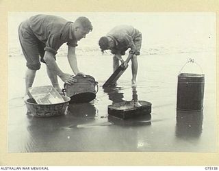 HANSA BAY-BOGIA HARBOUR, NEW GUINEA. 1944-08-09. N350547 PRIVATE A.A. BARBY (1) AND V170002 PRIVATE H.D. BENCE (2); COOKS OF NO. 13 PLATOON, C COMPANY, 30TH INFANTRY BATTALION SCOURING THEIR ..