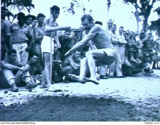 THE SOLOMON ISLANDS, 1945-01-12. A COMPETITOR STRIVES MIGHTLY DURING THE BROAD JUMP AT A COMBINED ANZAC SPORTS MEETING AT BOUGAINVILLE ISLAND. (RNZAF OFFICIAL PHOTOGRAPH.)