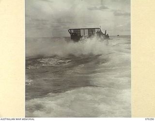 KELANOA AND BUTUBUTU, NEW GUINEA, 1944-02-08. A BARGE LOADED WITH TROOPS AND STORES OF HEADQUARTERS 5TH DIVISION SIGNALS, IN A ROUGH SEA BETWEEN KELANOA AND BUTUBUTU