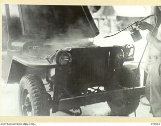 STIRLING ISLAND, TREASURY GROUP. 1945-03-21. VX89380 DRIVER A.V. HANSBURRY, 109TH BRIGADE WORKSHOP, ELECTRICAL AND MECHANICAL ENGINEERS, SPRAYING HIS JEEP
