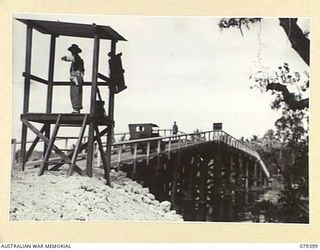 JACQUINOT BAY, NEW BRITAIN. 1945-02-27. AN AUSTRALIAN MILITARY POLICEMAN REGULATING THE TRAFFIC ACROSS THE NEW BRIDGE OVER THE KALUMALAGI RIVER BUILT BY PERSONNEL OF THE 13TH FIELD COMPANY