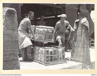 RABAUL, NEW BRITAIN, 1945-10-17. PERSONNEL OF SECTION 2, 8 FIELD BAKING PLATOON REMOVING A BATCH OF NEW LOAVES FROM THE OVEN. 6,600 POUNDS OF BREAD IS BAKED HERE DAILY GIVING EACH MAN IN ..