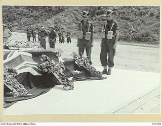 SALAMAUA, NEW GUINEA. 1944-04-30. QX59496 CORPORAL M. W. BARKER (1), WITH Q11404 SIGNALMAN C. SHUTZE (2), MEMBERS OF THE 42ND INFANTRY BATTALION, EXAMINE THE WREATHS ON THE CENOTAPH AFTER THE ..