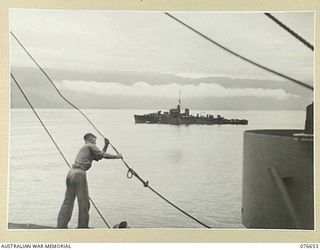 JACQUINOT BAY, NEW BRITAIN. 1944-11-04. AN ESCORTING NAVAL VESSEL MOVES ALONG CLOSE IN SHORE AS THE TROOPSHIP "CAPE ALEXANDER" ENTERS THE BAY WITH THE TROOPS OF THE 14/32ND INFANTRY BATTALION