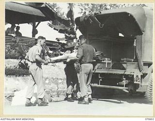 A NEW PATIENT BEING CARRIED FROM AN AMBULANCE INTO A WARD AT THE 2/1ST AUSTRALIAN GENERAL HOSPITAL