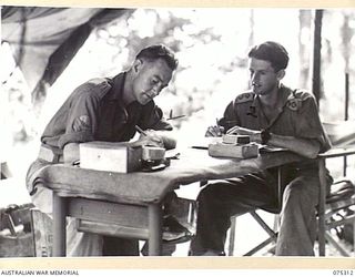 NAGADA, NEW GUINEA. 1944-08-16. VX104391 LIEUTENANT J.W. CLARKE, TROOP COMMANDER (2) DISCUSSING THE UNIT TRAINING PROGRAMME FOR PERSONNEL OF E TROOP, 22ND BATTERY, 106TH TANK ATTACK REGIMENT WITH ..