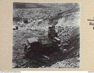 JACQUINOT BAY, NEW BRITAIN. 1945-04-13. RAAF ENGINEERS AT WORK WITH AN AUTOMATIC SHOVEL LOADING UP A TRUCK WITH CORANOUS SOIL FOR SPREADING ON THE NEW DISPERSAL BAYS BEING BUILT ON THE AIRSTRIP