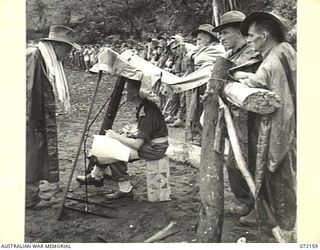 LAKONA, NEW GUINEA. 1944-04-08. TROOPS LINE THE RAILED OFF AREA AND STAND IN RAIN DURING THE 30TH INFANTRY BATTALION, 8TH INFANTRY BRIGADE SWIMMING CARNIVAL WATCHING THE EVENTS. NX123685 LIEUTENANT ..