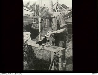 ALEXISHAFEN, NEW GUINEA. 1944-06-10. TX5918 PRIVATE D. J. SULZBERBER, 2/15TH FIELD AMBULANCE, MAKING SOUVENIRS FROM PARTS OF WRECKED JAPANESE AIRCRAFT FOUND ON THE AIRFIELD