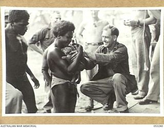 MILNE BAY, NEW GUINEA. 1943-06-29. NX27905 SAPPER E.E. MOORE OF "C" GROUP, 2/3RD AUSTRALIAN DOCKS OPERATING COMPANY, ROYAL AUSTRALIAN ENGINEERS, A.I.F., BARTERS WITH NATIVES OVER THE SALE OF ..