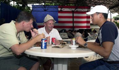 Commander (CDR) Tim Waterfield, United States Navy (USN), Destroyer Squadron One (DSRON), from Kaneohe, Hawaii (left), Lieutenant (LT) Patrick Gordocki, USN, from Hillsdale, New Jersey (center) and LT Henry Kim, USN, from Torrance, California, enjoy a 4th of July barbecue at the Terror Club in Singapore