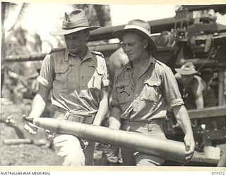 WUNUNG PLANTATION, JACQUINOT BAY, NEW BRITAIN. 1944-11-24. NX130454 LIEUTENANT S.G. HARMER, INSPECTING ORDNANCE OFFICER, 17TH ADVANCED AMMUNITION DEPOT (1) EXAMINING A 3.7" ANTI-AIRCRAFT GUN SHELL ..