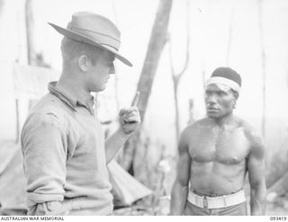 WEWAK AREA, NEW GUINEA. 1945-06-27. PRIVATE W.E. TRAPMAN, B COMPANY, 2/8 INFANTRY BATTALION (1), WHO IS IN CHARGE OF THE NATIVE CARRIERS, TALKING TO THE BOSS BOY AFTER THE NATIVE FOOD CARRIERS HAVE ..