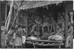 Mortuary ceremony: people gathered by house, participating in exchange ritual