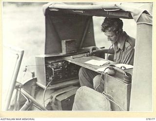 LAE, NEW GUINEA. 1945-01-03. VX86703 SIGNALLER G. MITCHELL, 34TH WIRELESS TELEGRAPHY SECTION (HEAVY) OPERATING A MOBILE RADIO STATION FROM A JEEP DURING TESTS CARRIED OUT BY THE 19TH LINES OF ..