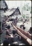 Canoe-building: man (center) says a spell while cutting vine rope from the hollowed out log