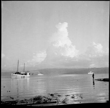 Man standing on boat ramp with three ships in the harbour and the Beehives, Rabaul Harbour, New Guinea, 1937 / Sarah Chinnery