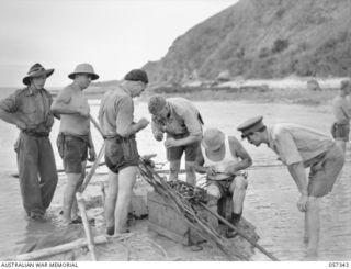 Technicians of the Signals Section (PMG Department) and soldiers form  New Guinea Force, in the process of laying cable between New Guinea and Cape York. The men are seen here splicing the shore ..