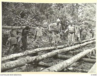 1943-01-14. ROAD BUILDERS FOLLOWING UP THE ADVANCING ALLIED TROOPS. TANKS SLITHERED ALONG THIS PATH IN THE FIGHT AGAINST THE JAPS AND INFANTRY CARRYING HEAVY EQUIPMENT, OFTEN SANK TO THEIR KNEES IN ..