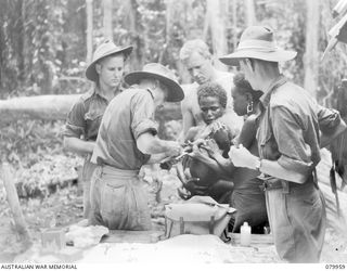 BOUGAINVILLE PURIATA RIVER. 1945-03-23. PERSONNEL OF THE 11TH FIELD AMBULANCE, AUSTRALIAN ARMY MEDICAL CORPS, IMMUNISING A PICCANINNY AGAINST YAWS DURING THE TREATMENT OF EVACUATED WOMEN AND ..